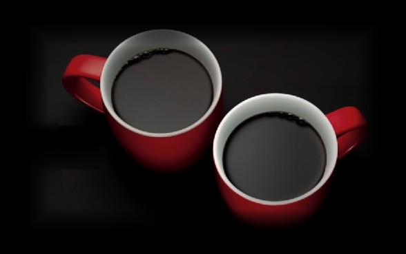 Zwei rote Kaffeetassen vor schwarzem Grund